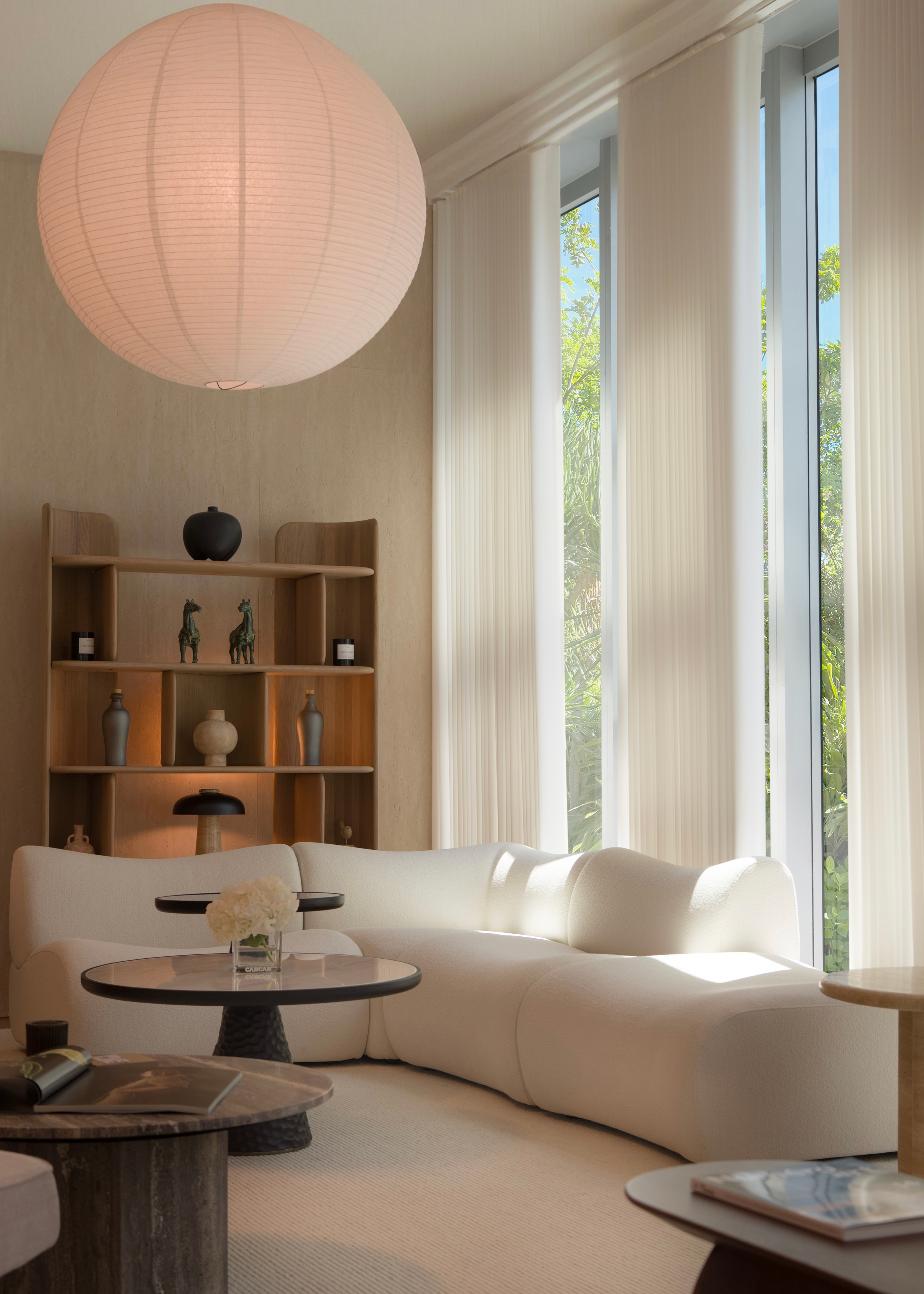 Modern living room with a white sofa, round lamp, and bookshelf.