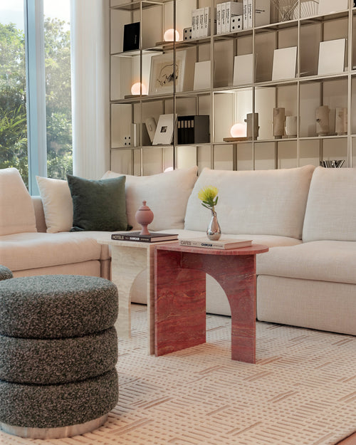 Modern living room with a beige sofa, ottoman, and decorative items on shelves.