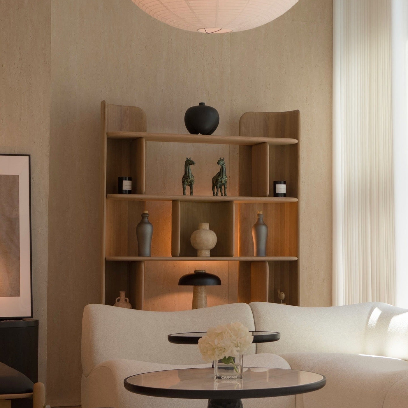 Modern living room with a white sofa, wooden bookshelf, and round table.