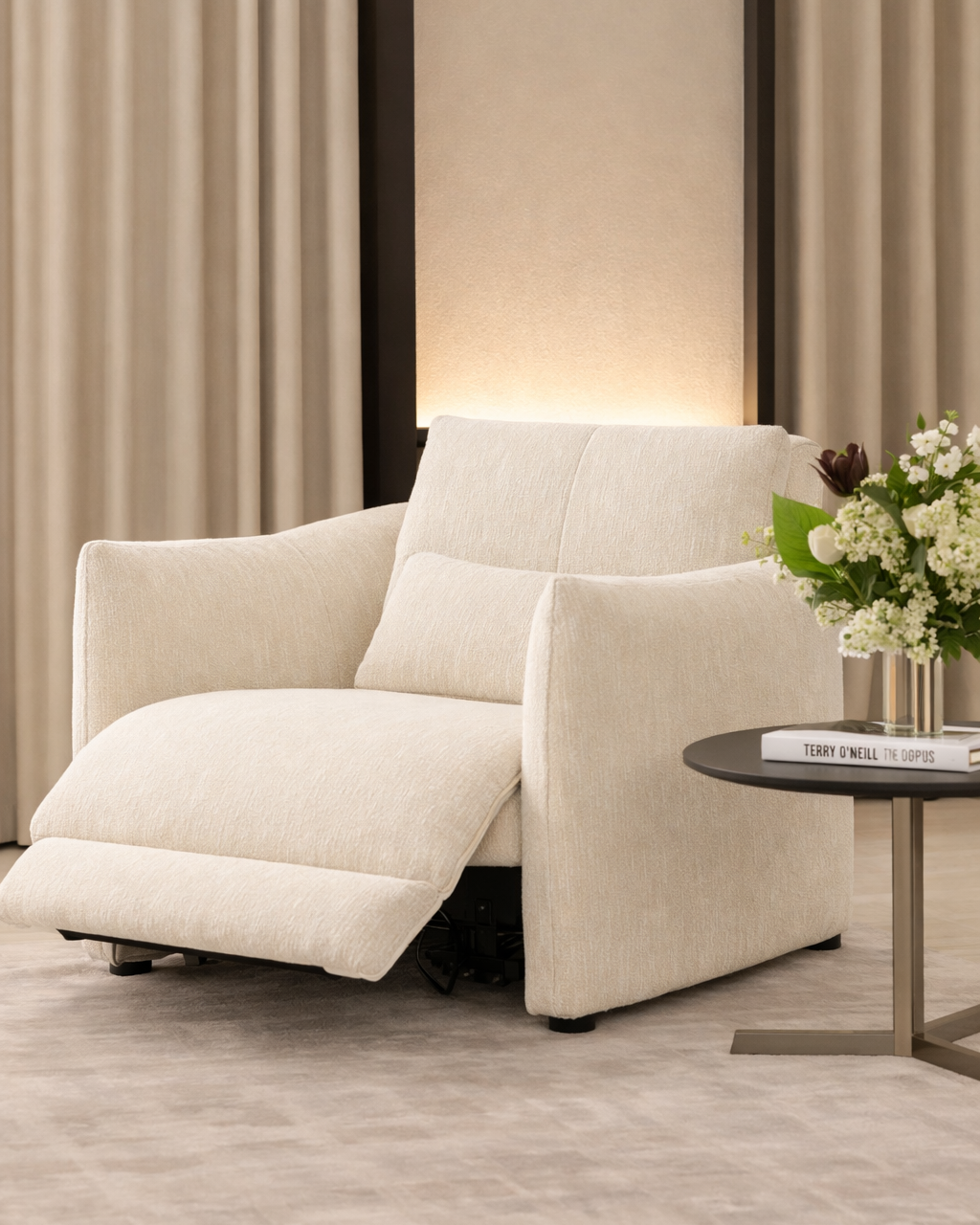 Beige recliner chair in a room with curtains and a small table with flowers.