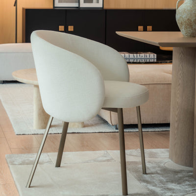 Modern dining room with white chairs, a round table, and decorative elements.