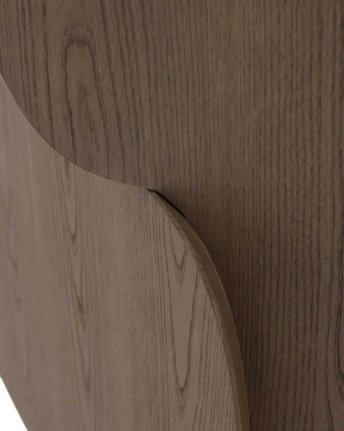 Close-up of a curved wooden surface with a medium brown wood grain finish, showing the texture and grain pattern in detail.
