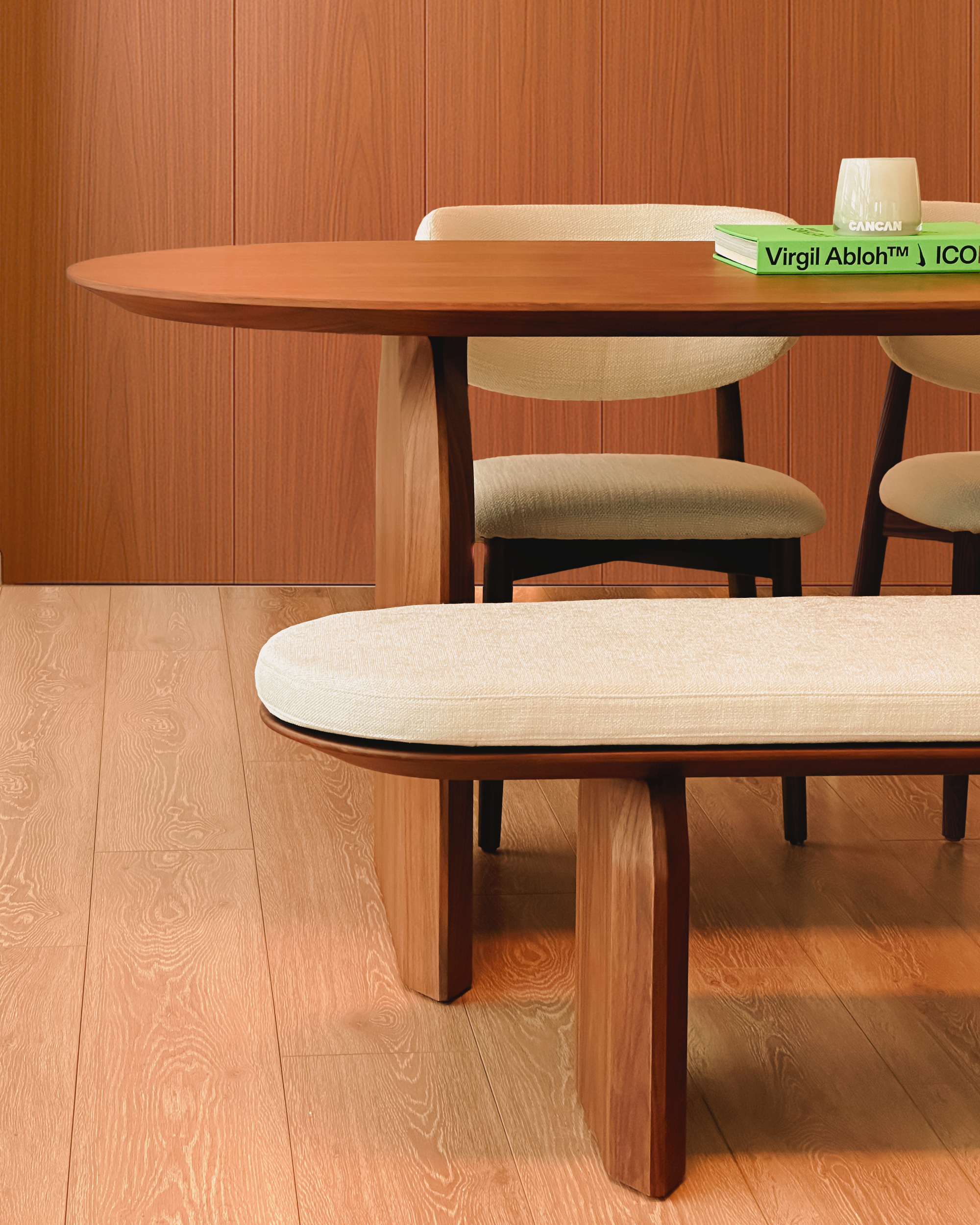 Wooden dining table with chairs and a bench in a room with wooden flooring and walls.