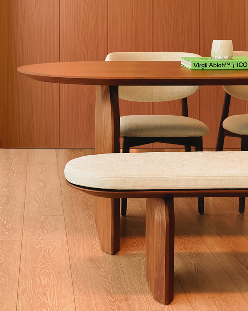 Wooden dining table with chairs and a bench in a room with wooden flooring and walls.