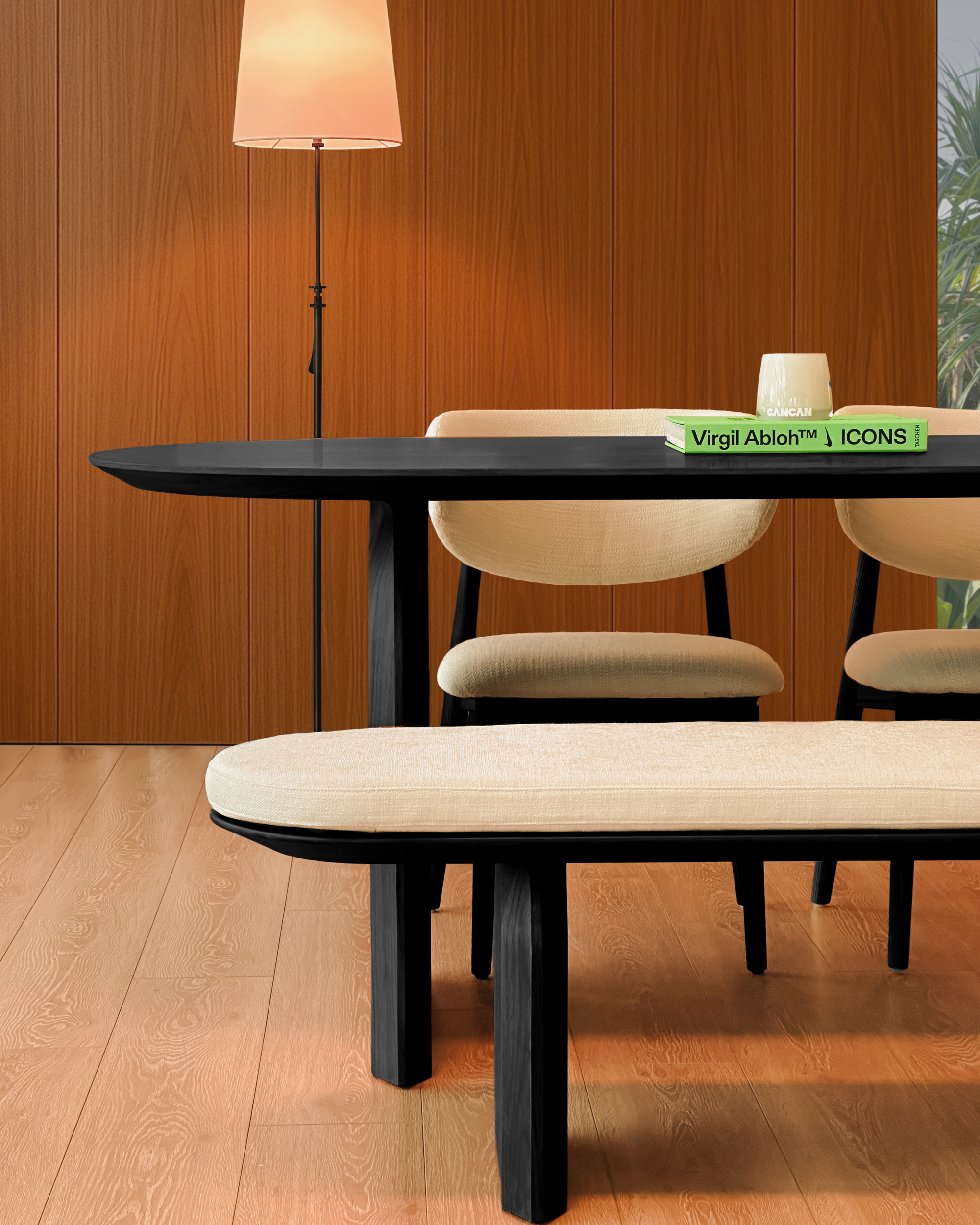 Dining room with a black table, beige chairs, and a lamp against a wooden wall.
