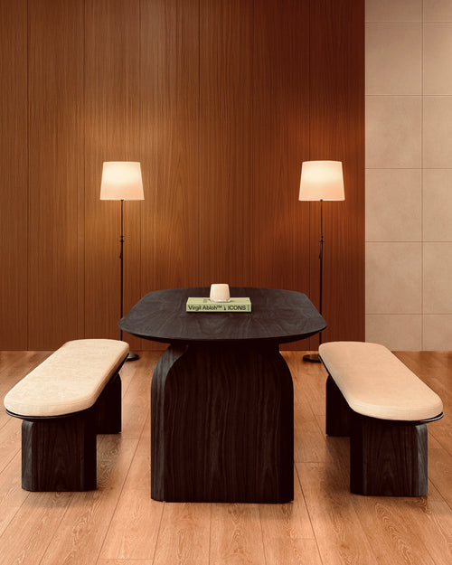 Modern dining set with dark wooden table and benches against a wooden wall.