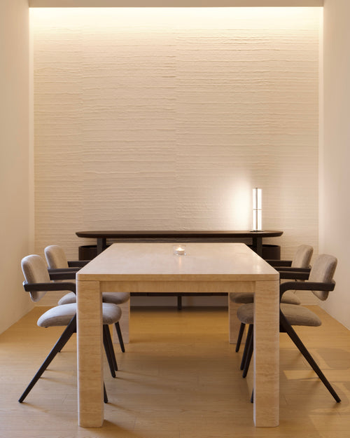 Modern dining area with a light wood table and chairs against a textured wall.