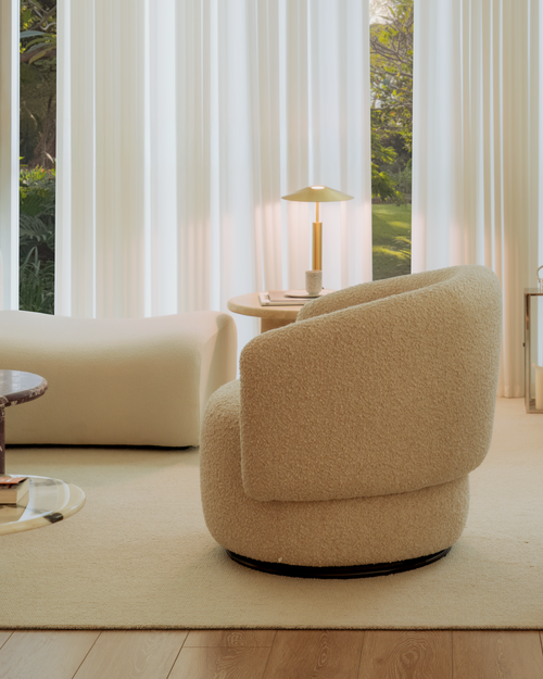 Beige armchair in a room with large windows and white curtains