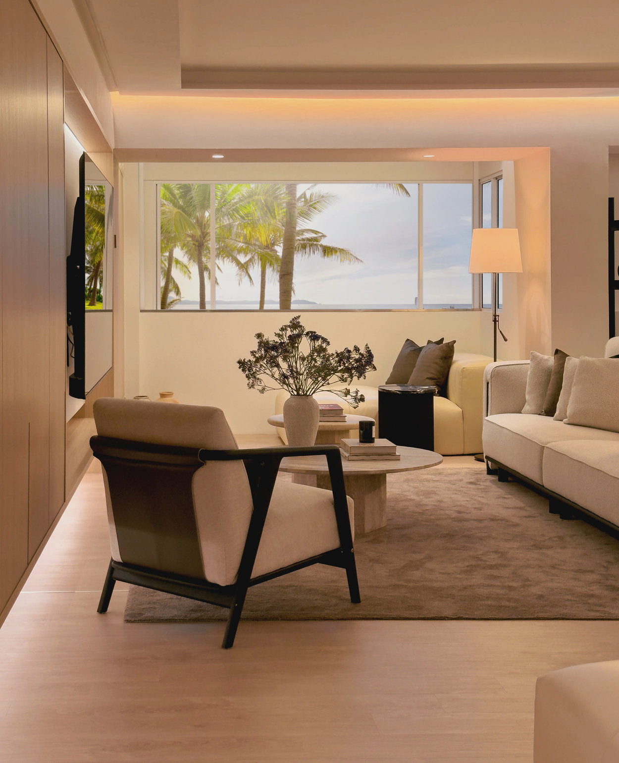 Modern living room with a view of palm trees and ocean.