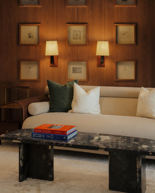 Living room with a beige sofa, marble coffee table, and framed pictures on the wall.
