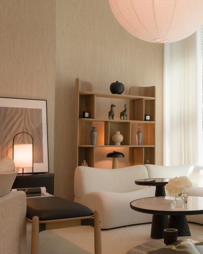 Modern living room with white sofa, wooden bookshelf, and large windows.