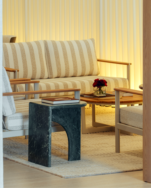 Modern living room with striped sofa, marble side table, and coffee table with flowers.