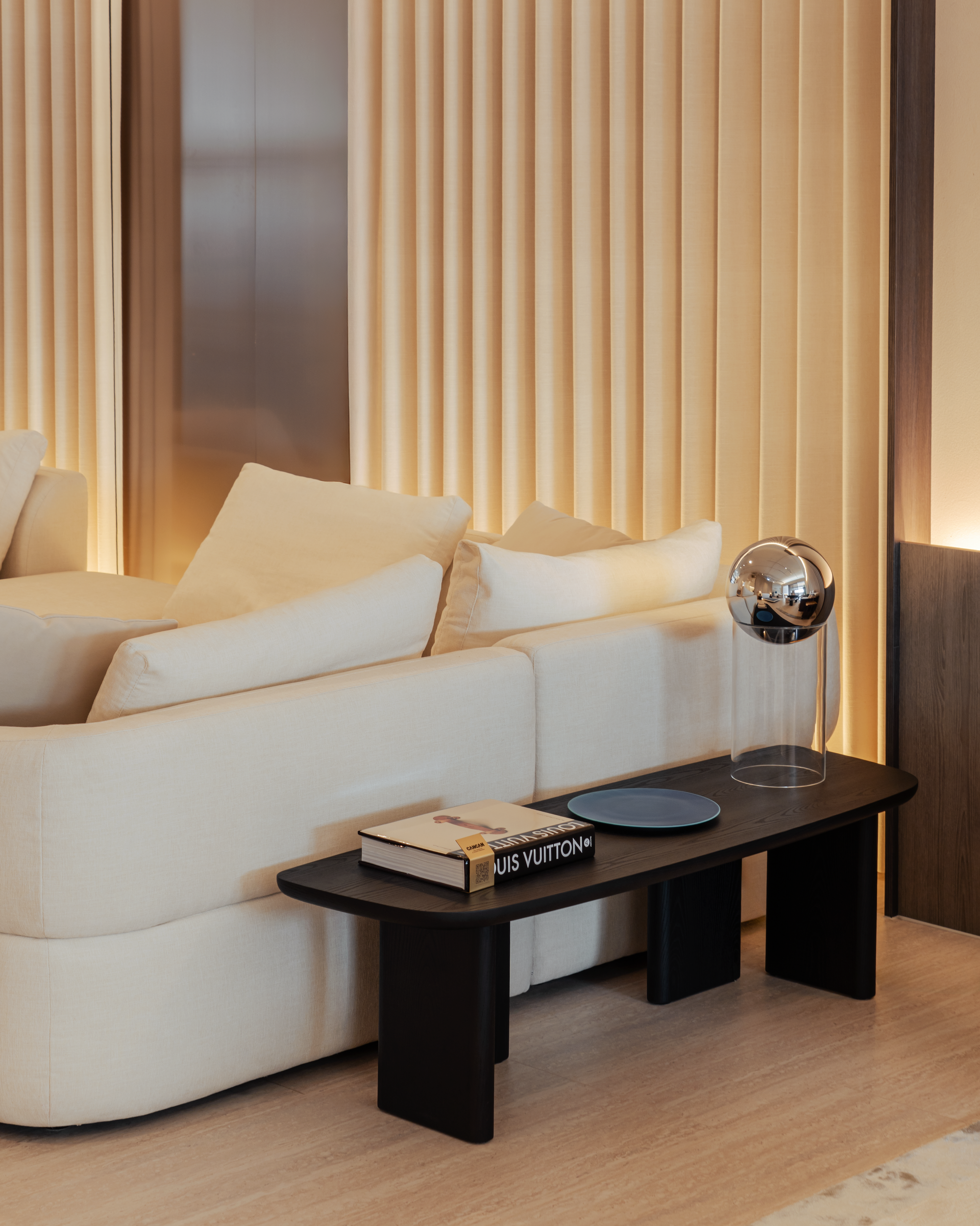 Modern living room with a beige sofa and a coffee table featuring a Louis Vuitton book.