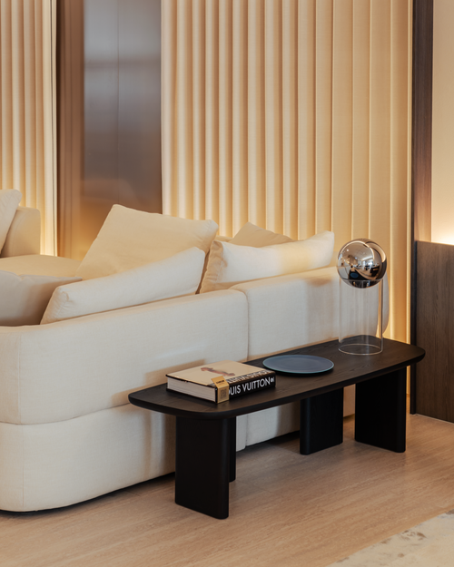 Modern living room with a beige sofa and a coffee table featuring a Louis Vuitton book.