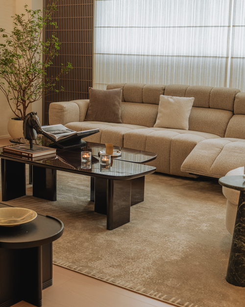 Modern living room with beige sectional sofa, coffee table, and decorative items.
