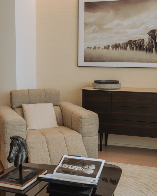 Living room with beige armchair, coffee table, and framed artwork on wall