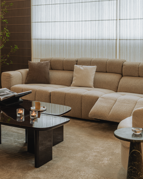 Beige sectional sofa in a modern living room with glass coffee table and decorative elements.