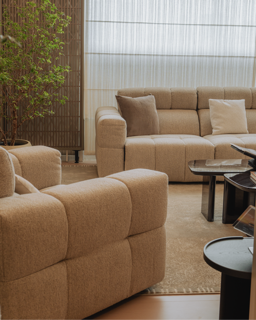 Beige sectional sofa in a living room with a plant and coffee table.
