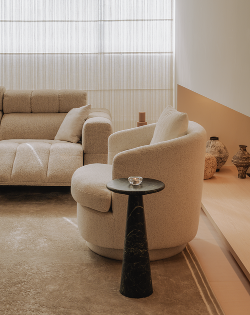Modern living room with beige sofa and armchair, black side table, and decorative vases.
