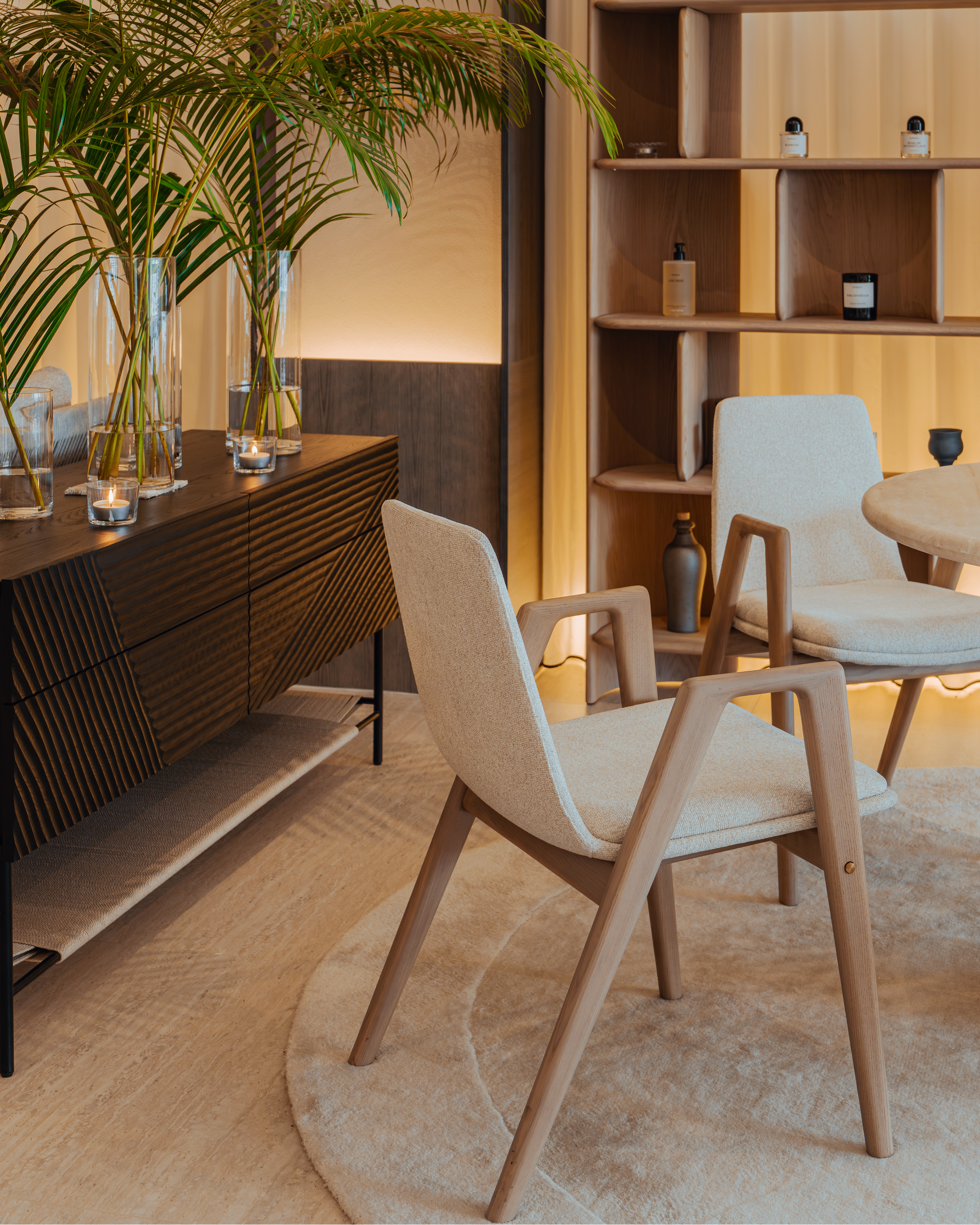 Modern interior with wooden chairs, a bookshelf, and decorative plants.