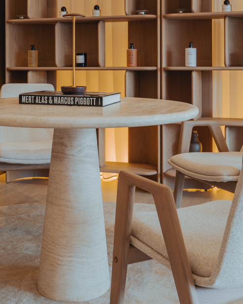 Wooden table with books and chairs in a room with wooden shelves.