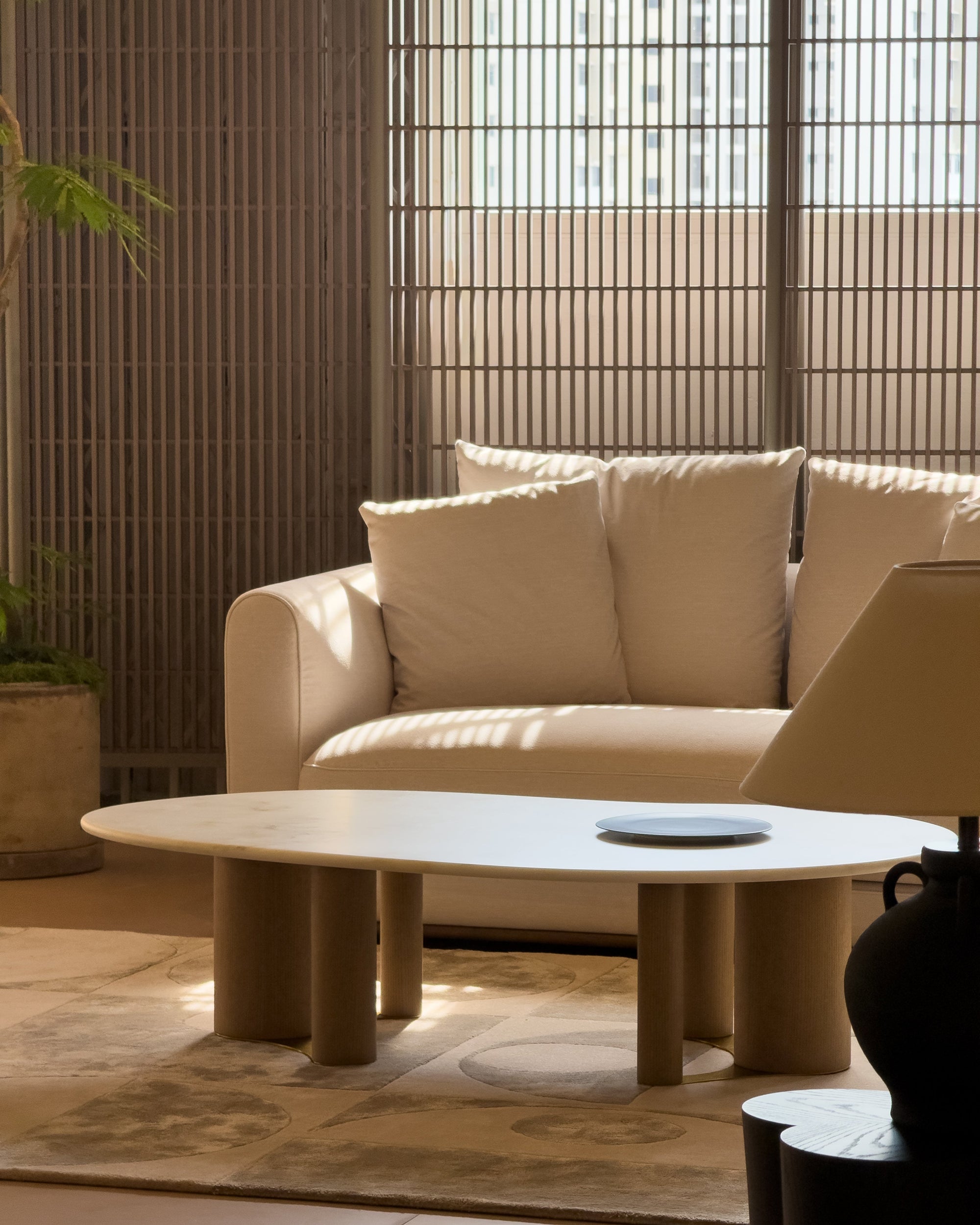 Beige sofa with a round coffee table in a room with bamboo walls.