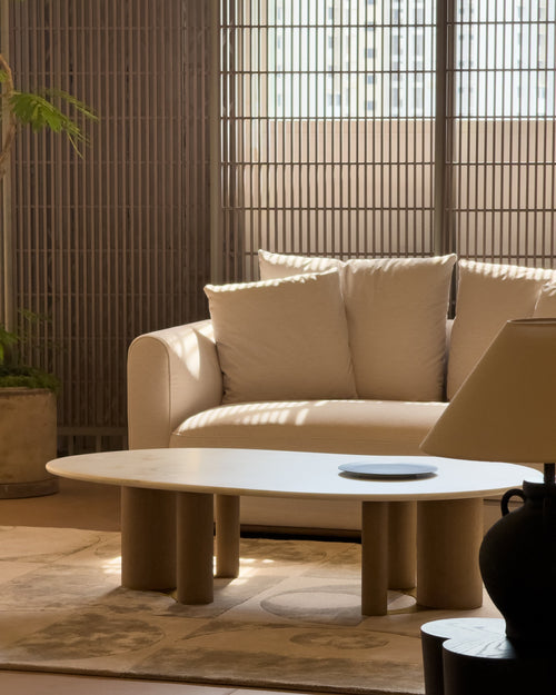 Beige sofa with a round coffee table in a room with bamboo walls.