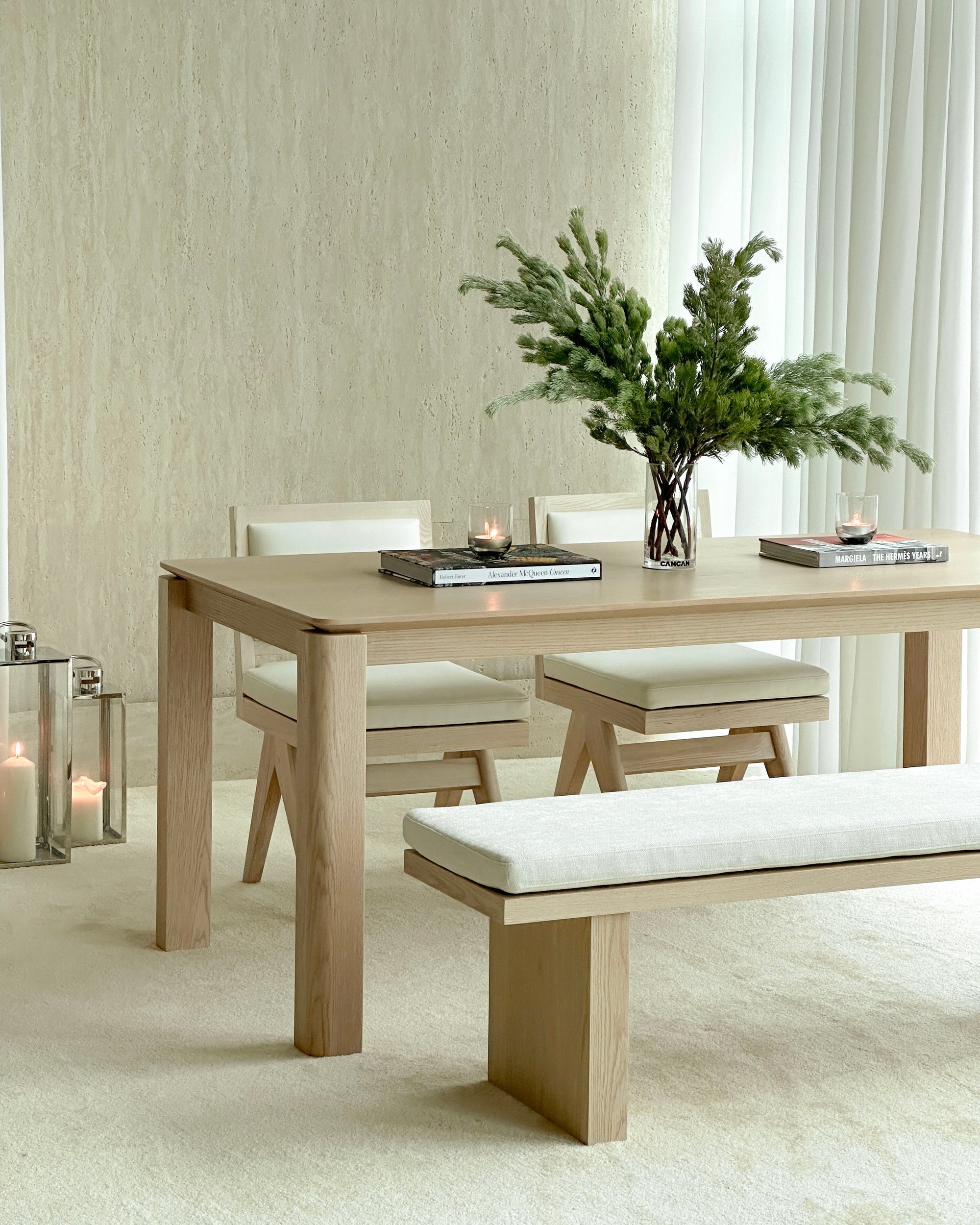 Dining room with wooden table, chairs, and bench against a neutral wall.