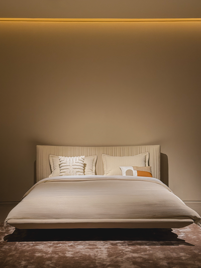 Beige bed with pillows against a beige wall in a bedroom setting