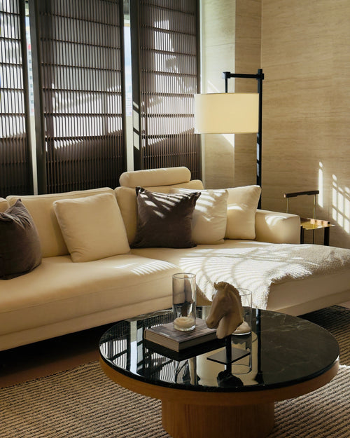 Modern living room with beige sofa, round black coffee table, and decorative items.