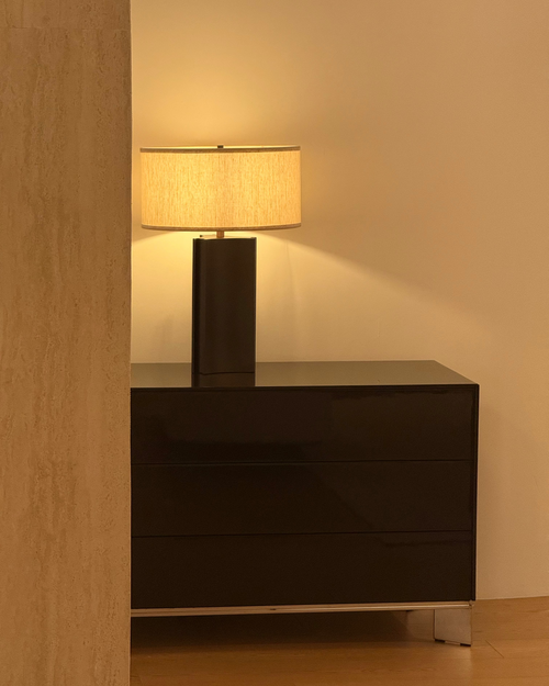 Dark wooden dresser with a lamp on a beige wall background