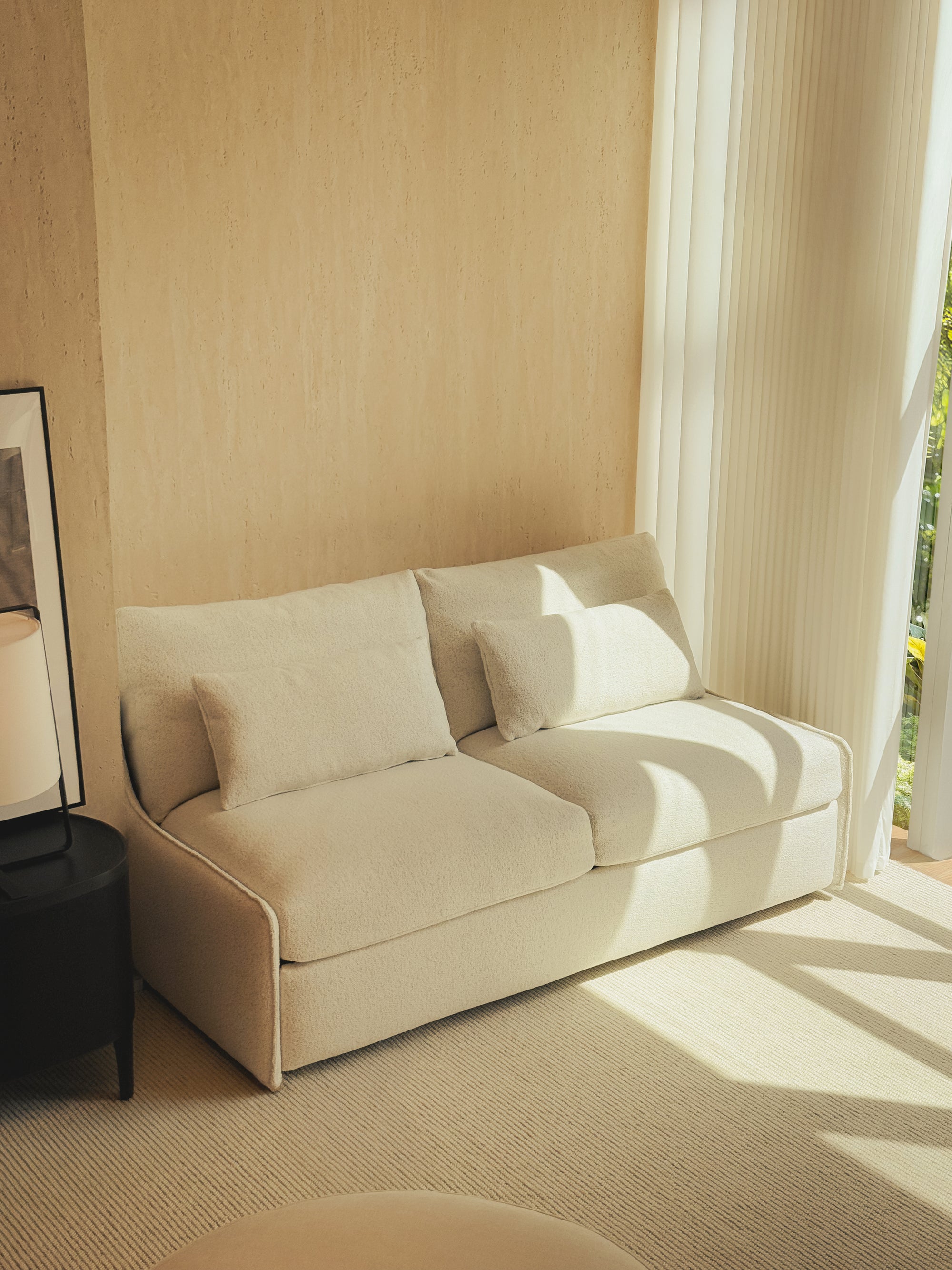 Beige sofa in a room with sunlight streaming through a window.