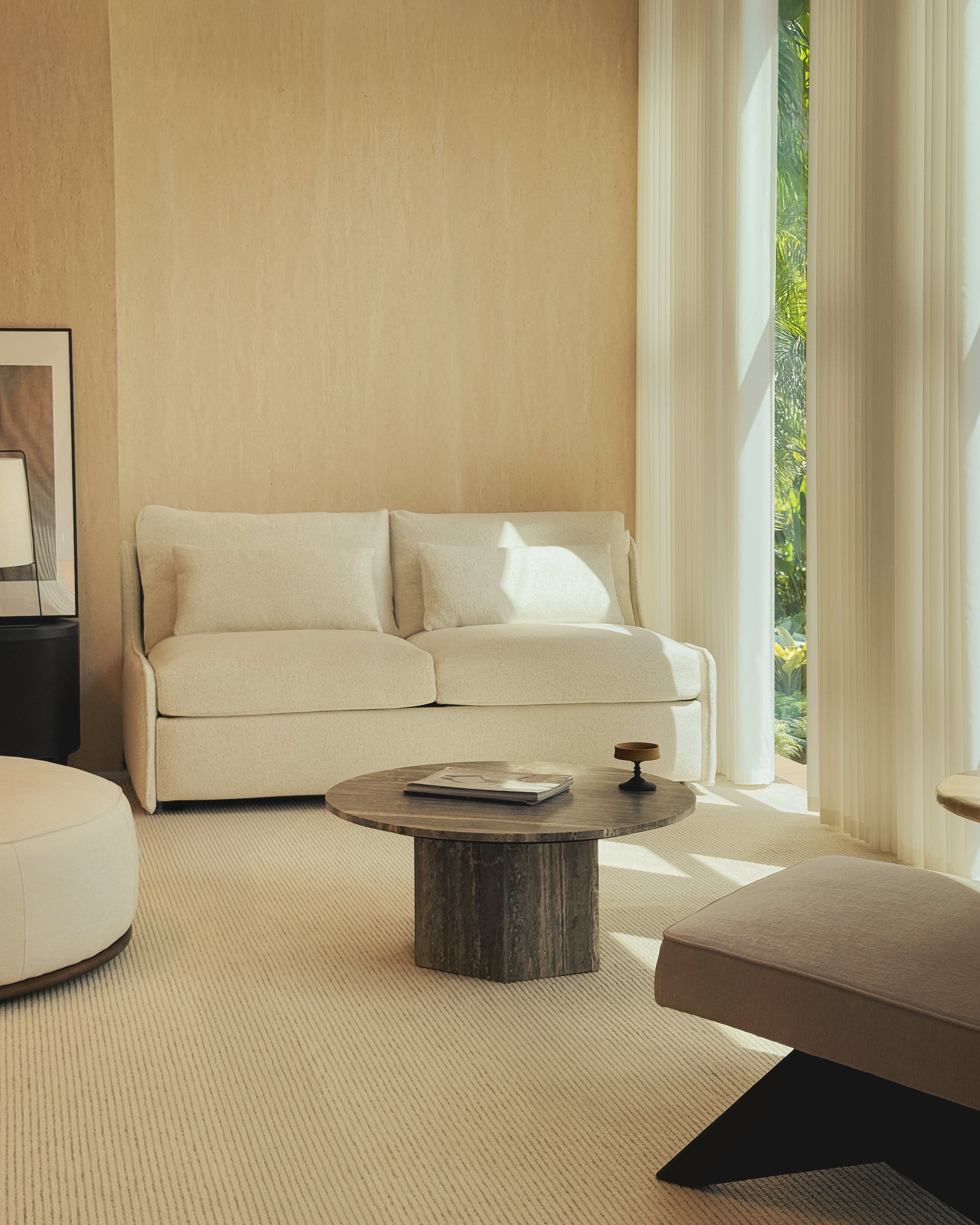 Modern living room with beige sofa, round wooden coffee table, and large window.