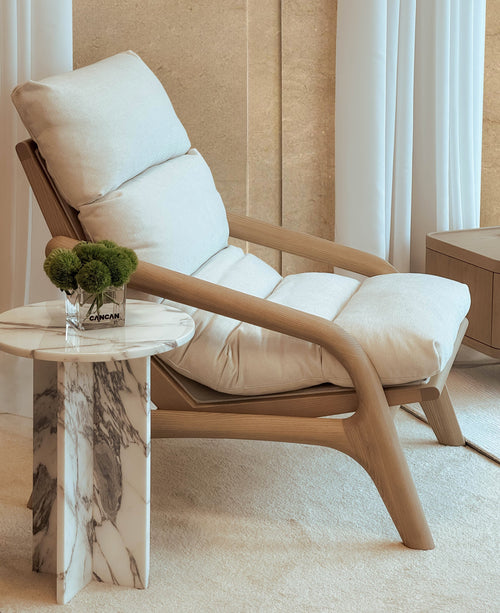 Modern beige recliner chair in a room with a marble side table and decorative plant.