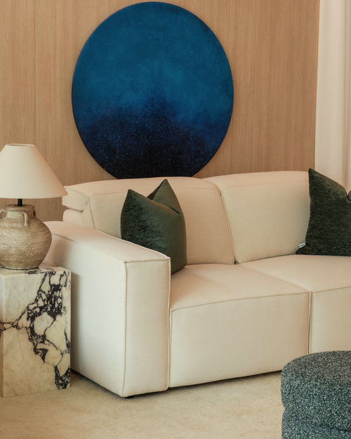 Beige sofa with green pillows in a living room setting