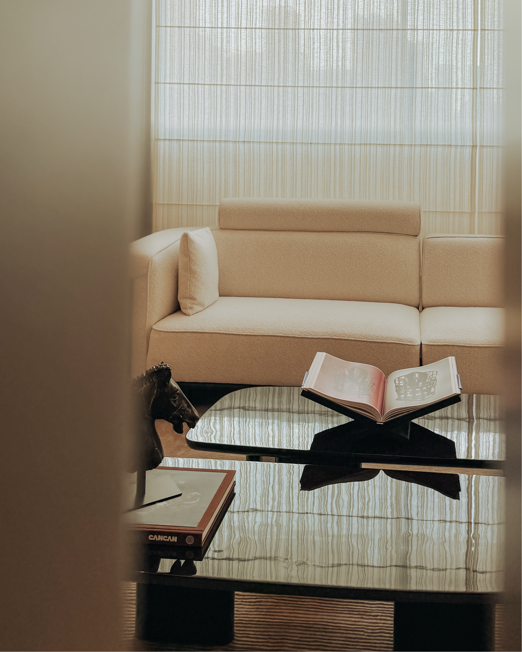 Beige sofa in a room with a glass coffee table and an open book.