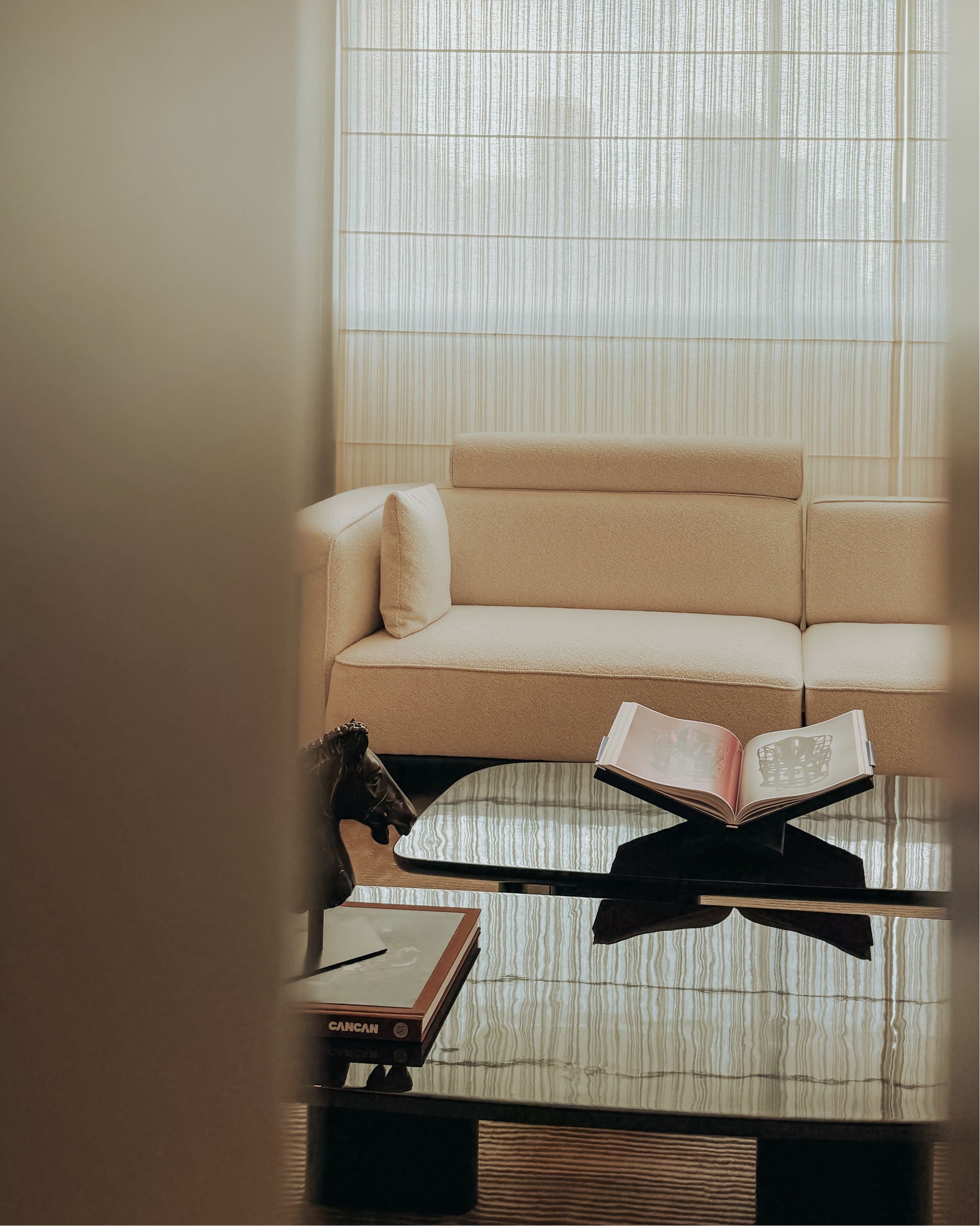 Beige sofa in a room with a glass coffee table and an open book.