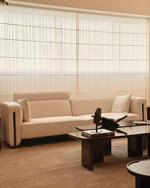 Beige sofa in a modern living room with a glass coffee table and decorative items.