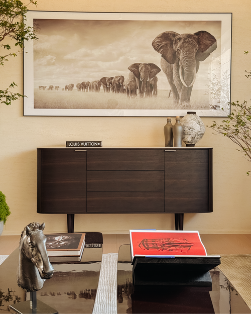 Decorative interior with a large framed picture of elephants, a Louis Vuitton box, and a horse sculpture.