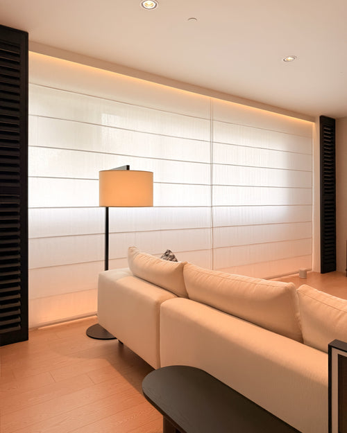 Modern living room with a white sofa, floor lamp, and decorative pillows.