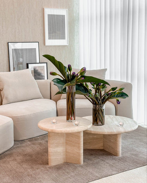 Modern living room with beige sofa, Travertine coffee table, and decorative plants.