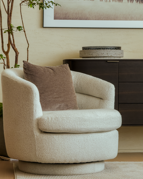 Beige armchair with a brown pillow in a living room setting