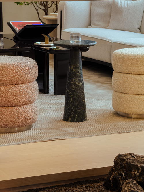 Modern living room with a marble side table, beige sofa, and textured ottomans.