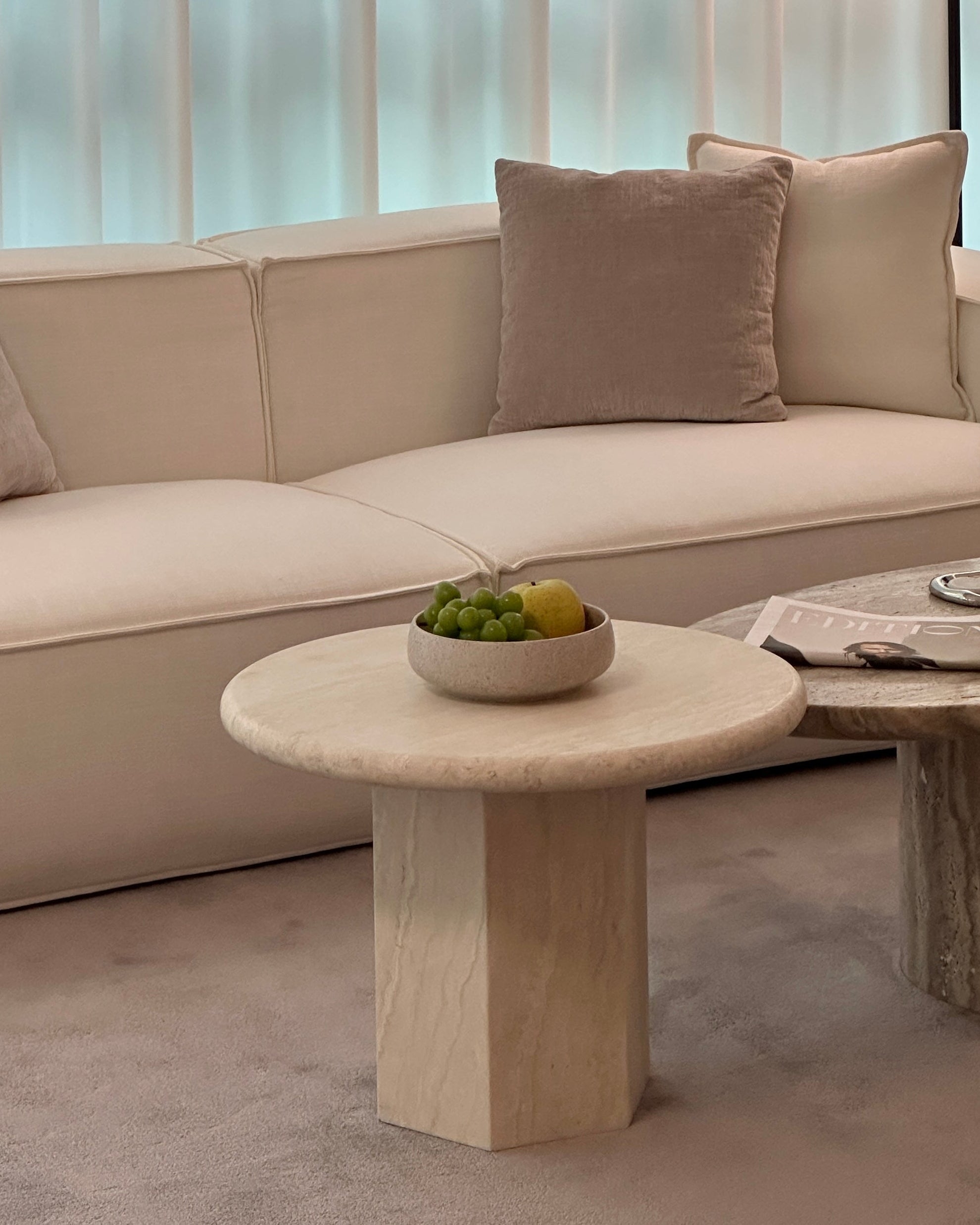 Modern living room with a beige sofa, marble coffee table, and wooden side table.