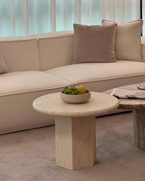 Modern living room with a beige sofa, marble coffee table, and wooden side table.