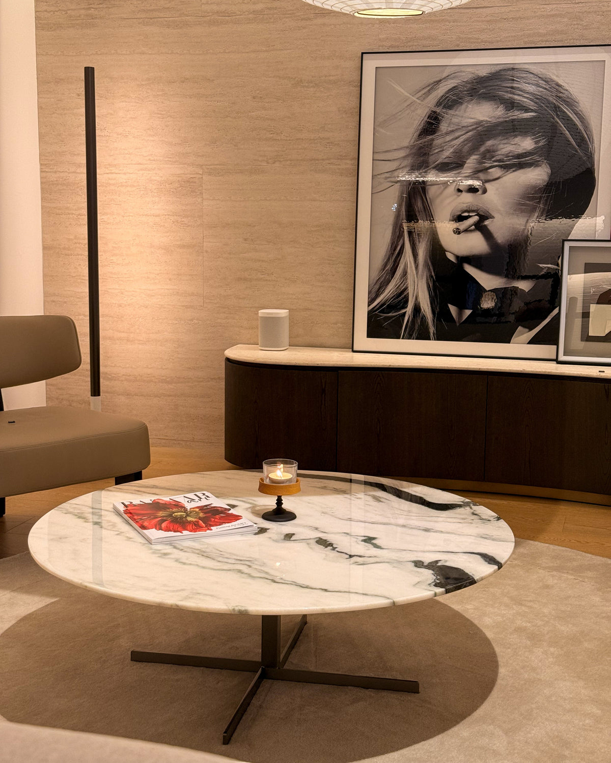 A modern round coffee table with a white and gray marble top and black metal cross base, styled in a contemporary living room setting.