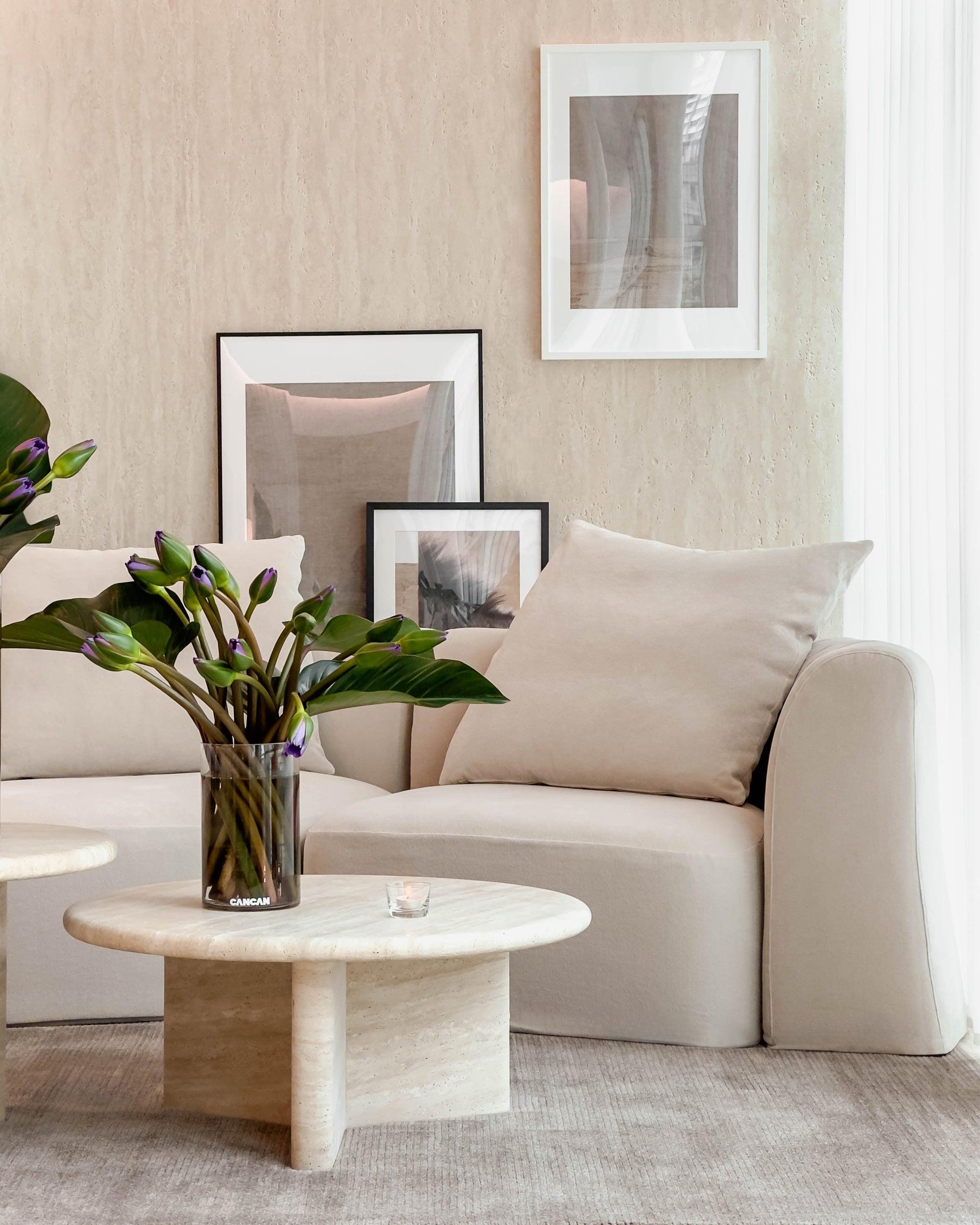 Modern living room with beige sofa, marble coffee table, and framed art on the wall.