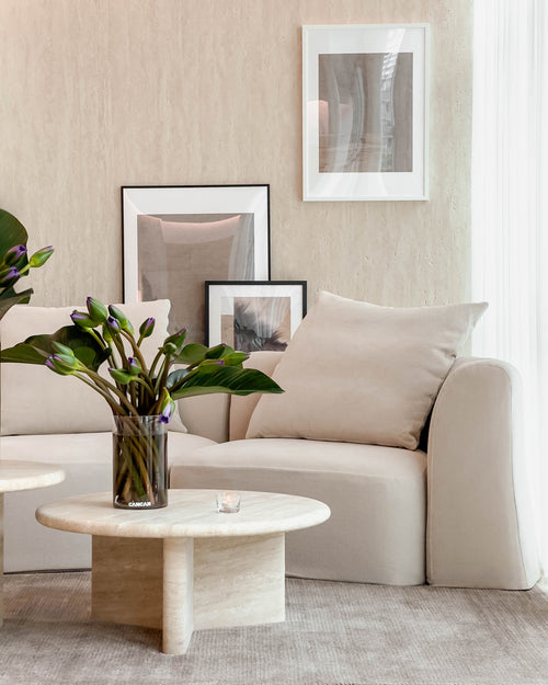 Modern living room with beige sofa, marble coffee table, and framed art on the wall.
