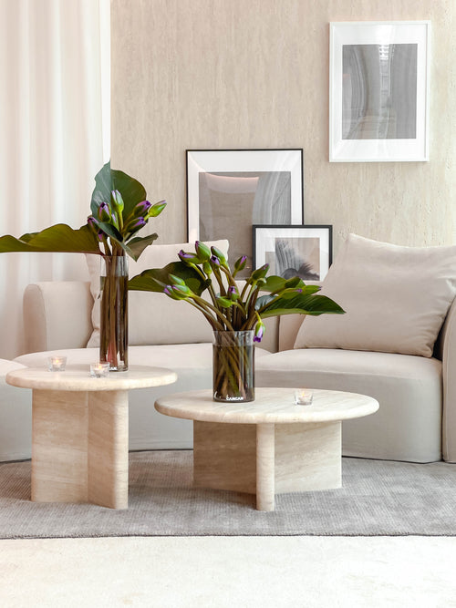 Modern living room with beige sofa, round coffee table, and decorative vases.