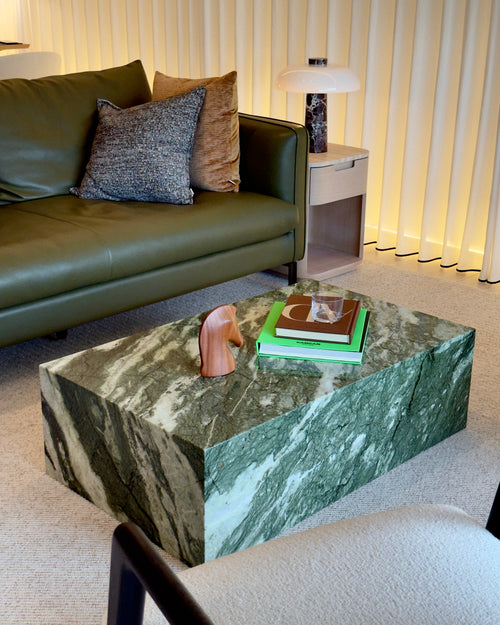 Green marble coffee table in a living room with a green sofa and decorative items.